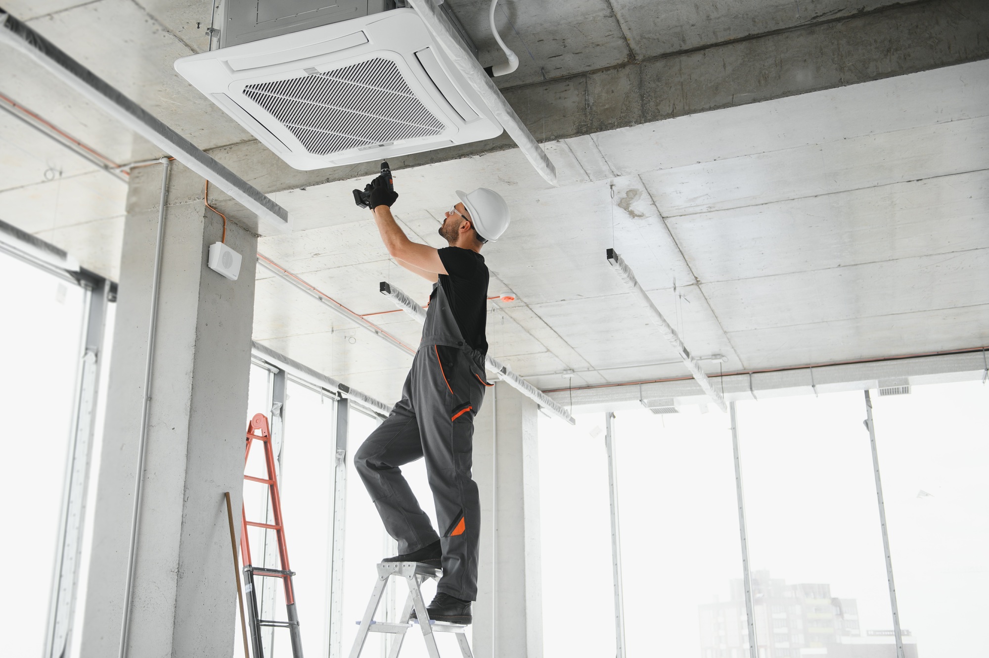 Worker repairing ceiling air conditioning unit
